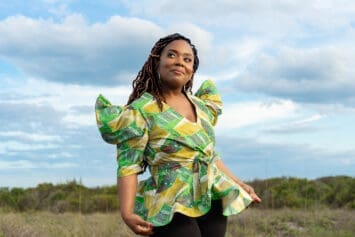 African American woman wearing McCalls 8146 pattern in green Ankara in an open field