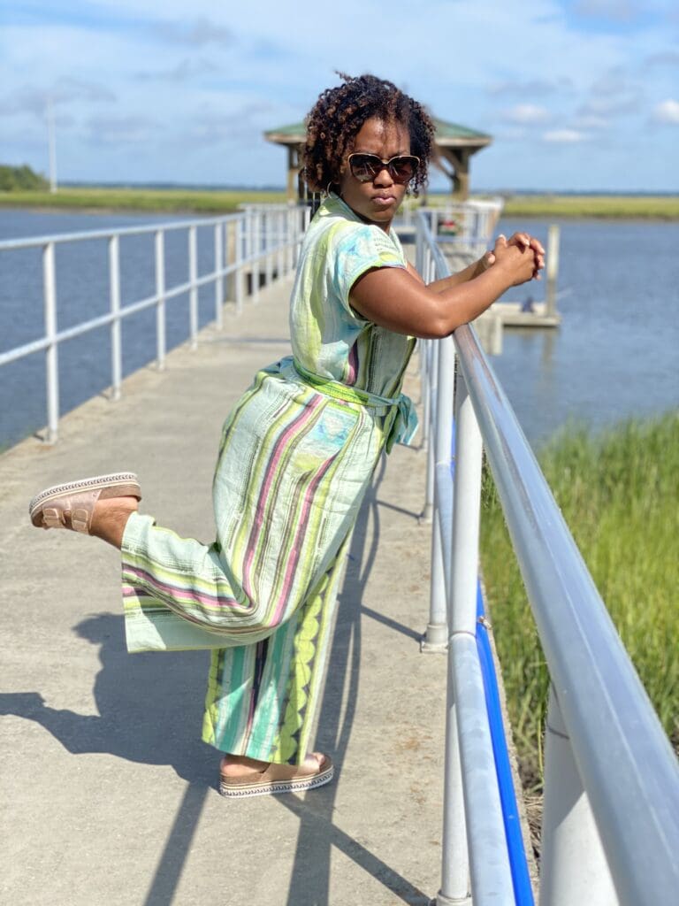 African American woman wearing the zadie jumpsuit by paper theory on a pier