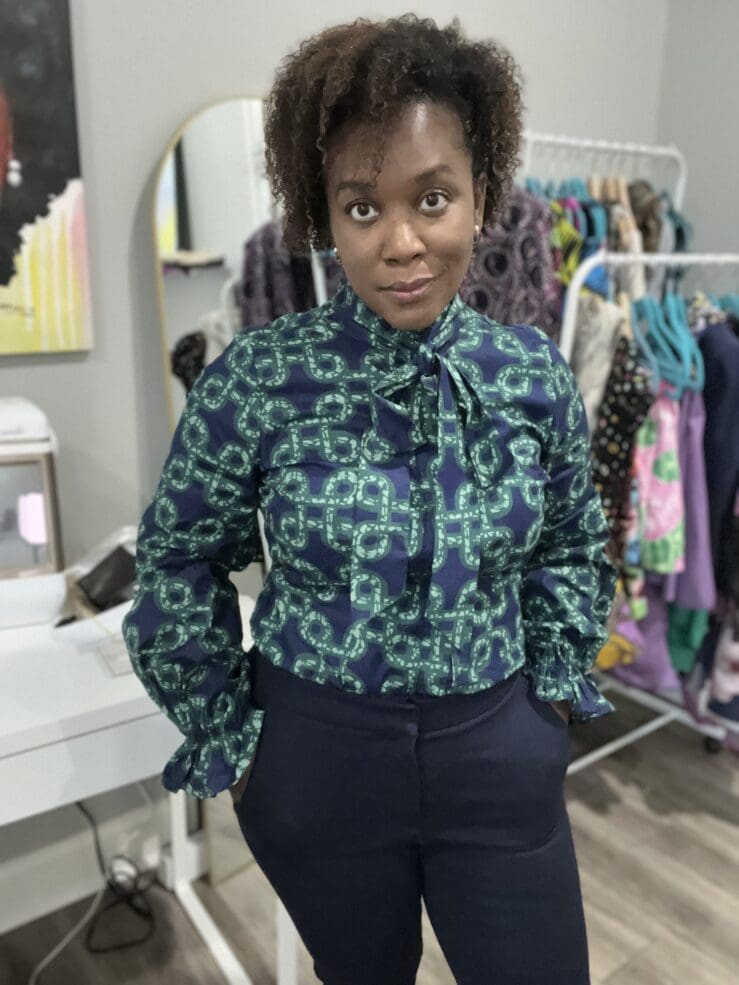 African America Woman standing wearing D'iyanu Akinyi blouse with navy pants