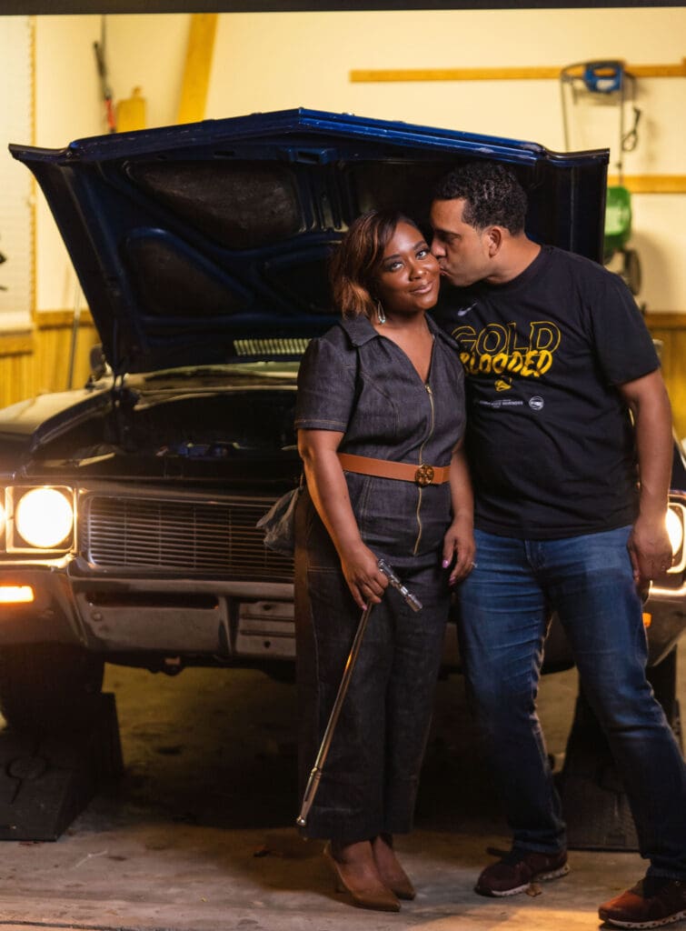 African American women holding car tool in front of car wearing McCalls7908 getting a kiss from man